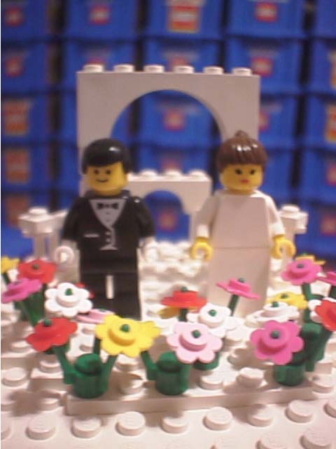 The minifig bride and groom atop the cake Four different colors of flowers